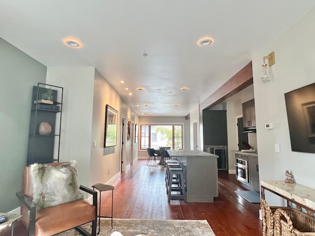 living room featuring dark wood-style flooring, recessed lighting, baseboards, and beverage cooler