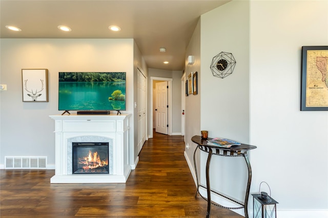 living room with recessed lighting, wood finished floors, baseboard heating, baseboards, and a glass covered fireplace