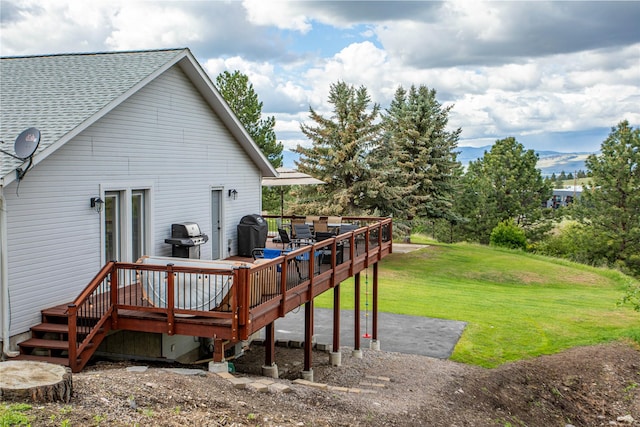 rear view of house featuring a yard, a shingled roof, a wooden deck, and outdoor dining space