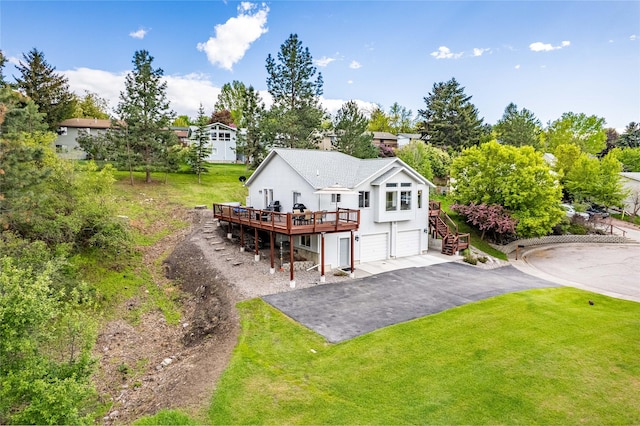 back of property featuring stairs, an attached garage, a deck, a lawn, and asphalt driveway