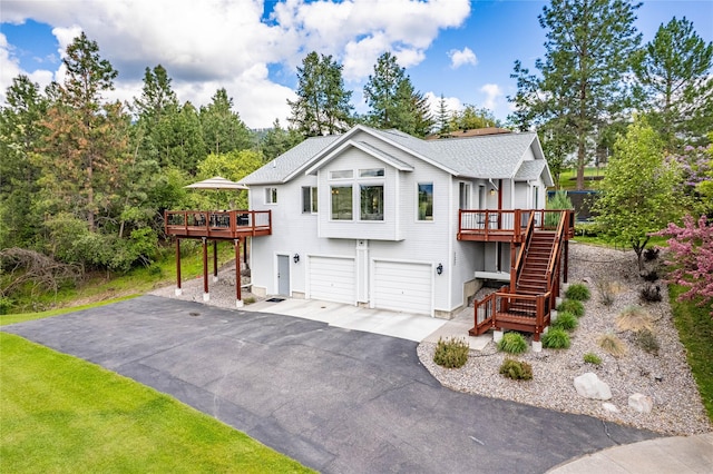 view of front of home featuring stairway, driveway, a garage, and a wooden deck