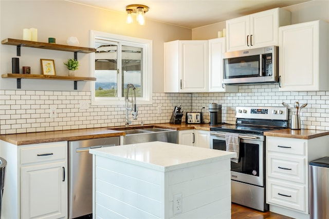 kitchen featuring stainless steel appliances, a sink, a kitchen island, and backsplash