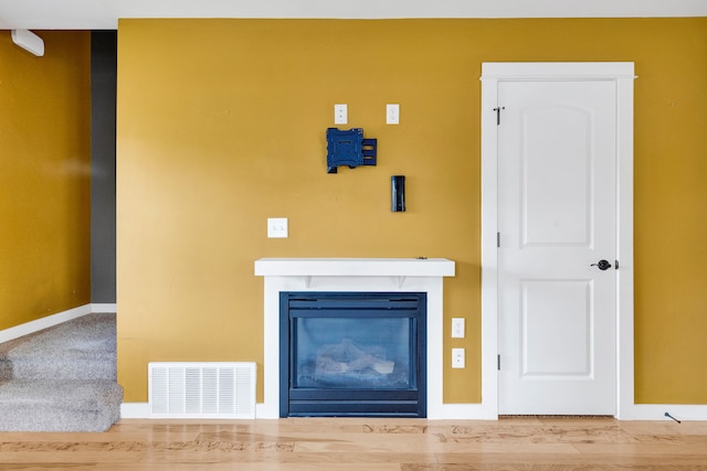unfurnished living room with a glass covered fireplace, baseboards, and wood finished floors