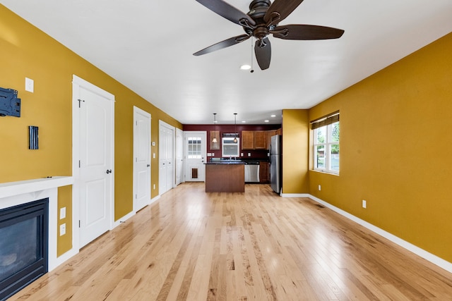 unfurnished living room with light wood-style floors, a ceiling fan, a high end fireplace, and recessed lighting