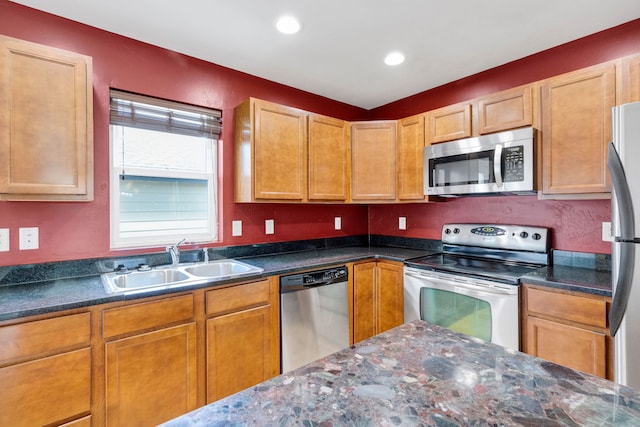 kitchen with stainless steel appliances, a sink, recessed lighting, and dark stone counters