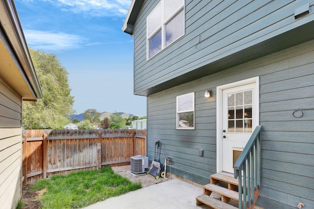 view of patio / terrace with fence, entry steps, a mountain view, and central AC unit