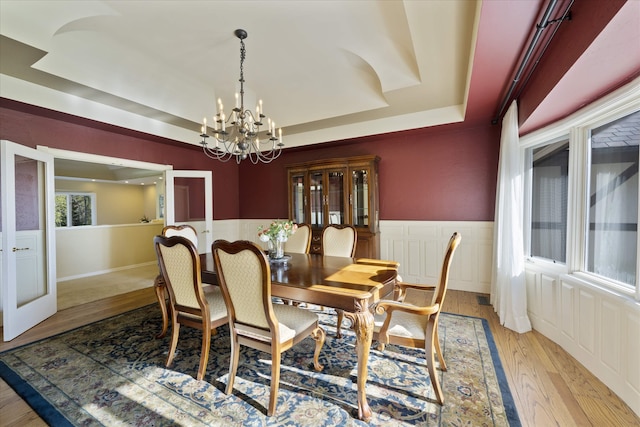 215 Browns Gulch Rd, Kalispell, MT 59901 - dining area with a tray ceiling, a chandelier, light wood-style floors, and a wainscoted wall