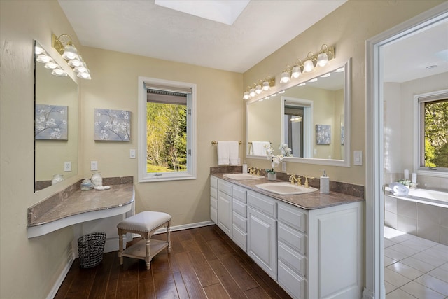 215 Browns Gulch Rd, Kalispell, MT 59901 - bathroom with double vanity, a garden tub, wood finished floors, baseboards, and a skylight