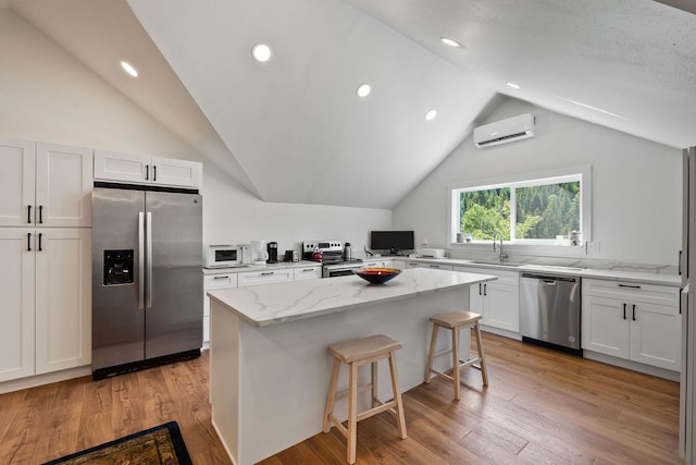 215 Browns Gulch Rd, Kalispell, MT 59901 - kitchen featuring appliances with stainless steel finishes, an AC wall unit, lofted ceiling, a sink, and light stone countertops