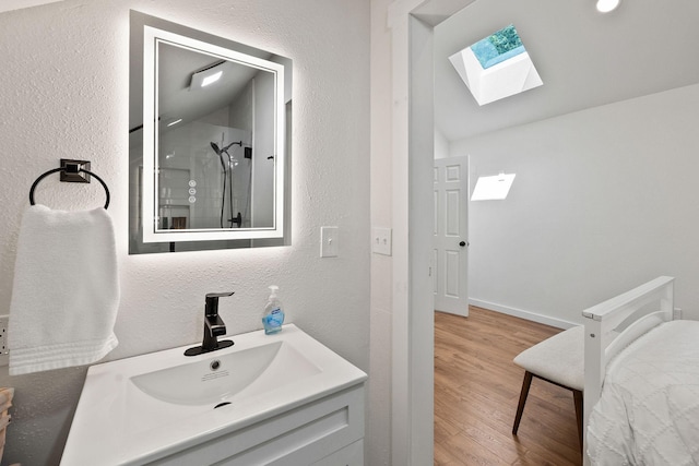 215 Browns Gulch Rd, Kalispell, MT 59901 - bathroom with a skylight, vanity, wood finished floors, a textured wall, and lofted ceiling