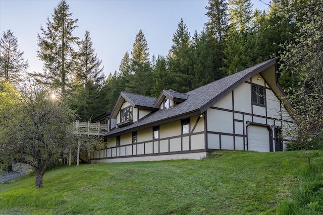 215 Browns Gulch Rd, Kalispell, MT 59901 - view of side of property featuring a lawn, stucco siding, a shingled roof, and a garage