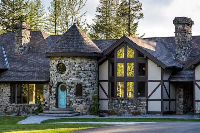 215 Browns Gulch Rd, Kalispell, MT 59901 - view of front of house with stone siding, a chimney, stucco siding, and a high end roof