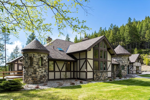 215 Browns Gulch Rd, Kalispell, MT 59901 - back of property with stucco siding, stone siding, a yard, and a chimney