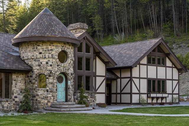 215 Browns Gulch Rd, Kalispell, MT 59901 - exterior space featuring stucco siding, stone siding, a high end roof, a view of trees, and a front yard