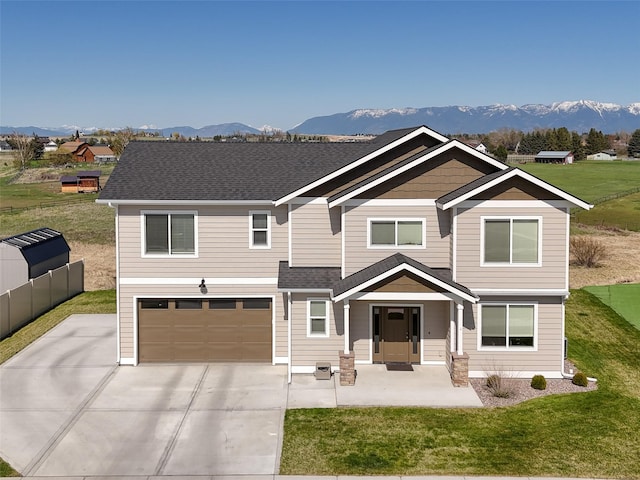 view of front of property featuring a mountain view, an attached garage, and a front yard