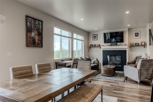 dining area with recessed lighting, light wood-type flooring, and a glass covered fireplace