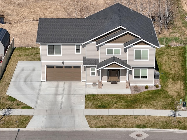 view of front of home featuring concrete driveway, a shingled roof, an attached garage, and a front lawn