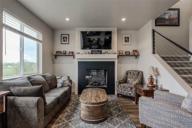 living room with wood finished floors, a glass covered fireplace, stairs, and recessed lighting