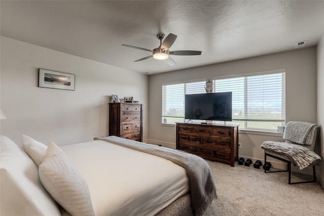 bedroom featuring light carpet, multiple windows, a ceiling fan, and baseboards