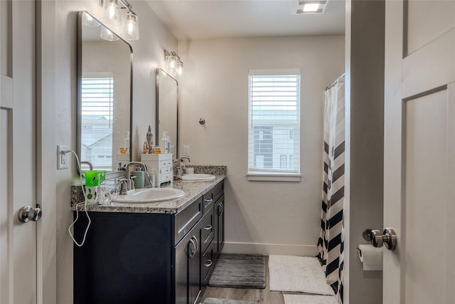 full bathroom with healthy amount of natural light, double vanity, and baseboards