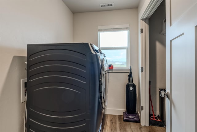 laundry room with wood finished floors, baseboards, and washer and dryer