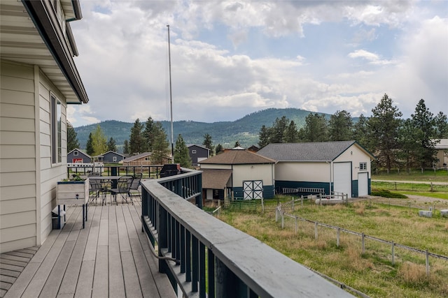 527 Grande Vista Dr, Kalispell, MT 59901 - wooden terrace featuring a mountain view, fence, an outdoor structure, and outdoor dining space