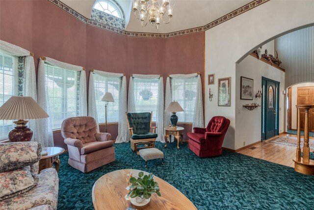 527 Grande Vista Dr, Kalispell, MT 59901 - carpeted living area featuring arched walkways, a high ceiling, a chandelier, baseboards, and wood finished floors