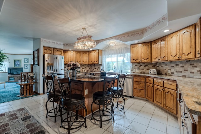 527 Grande Vista Dr, Kalispell, MT 59901 - kitchen featuring stainless steel appliances, a kitchen breakfast bar, brown cabinetry, and light tile patterned floors