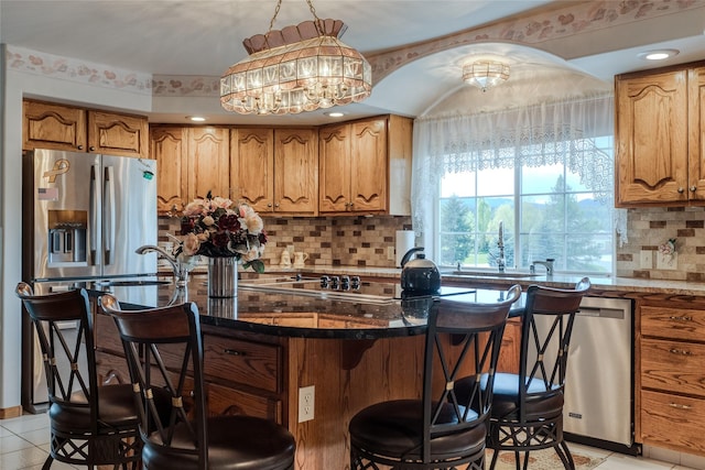 527 Grande Vista Dr, Kalispell, MT 59901 - kitchen featuring a kitchen bar, light tile patterned floors, decorative backsplash, brown cabinetry, and recessed lighting