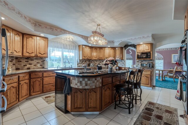 527 Grande Vista Dr, Kalispell, MT 59901 - kitchen with arched walkways, black microwave, a sink, and brown cabinets