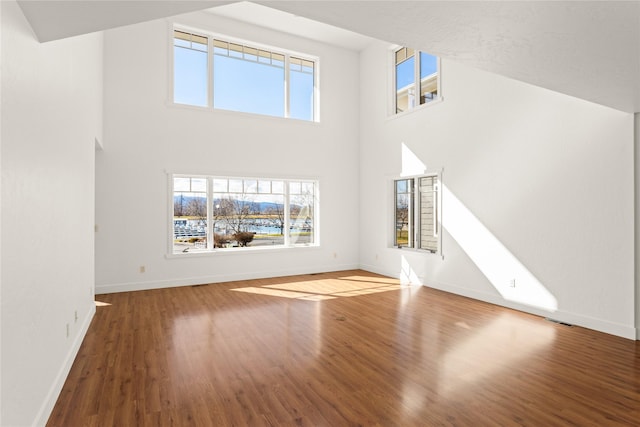 2060 Marina Ct, Bigfork, MT 59911 - unfurnished living room featuring wood finished floors, baseboards, and a towering ceiling
