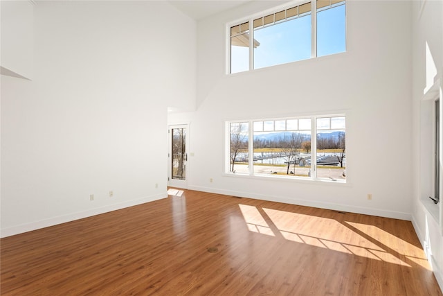 2060 Marina Ct, Bigfork, MT 59911 - unfurnished living room with a towering ceiling, baseboards, and wood finished floors