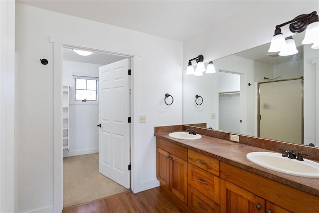 2060 Marina Ct, Bigfork, MT 59911 - bathroom featuring wood finished floors, a stall shower, double vanity, a walk in closet, and baseboards