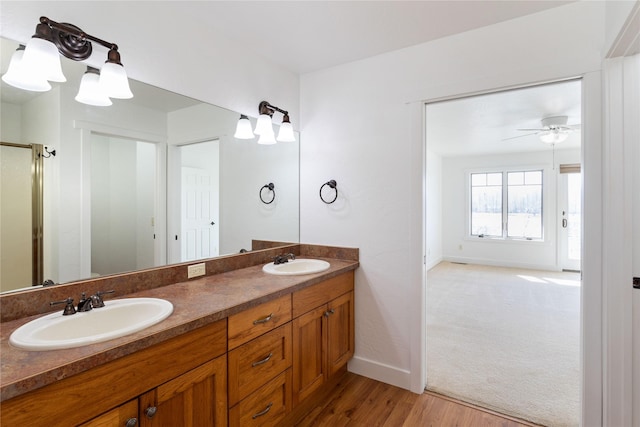 2060 Marina Ct, Bigfork, MT 59911 - bathroom featuring baseboards, double vanity, wood finished floors, ceiling fan, and a shower with door