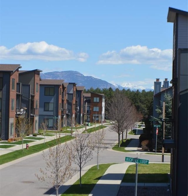view of asphalt street featuring a mountain view, sidewalks, and a residential view
