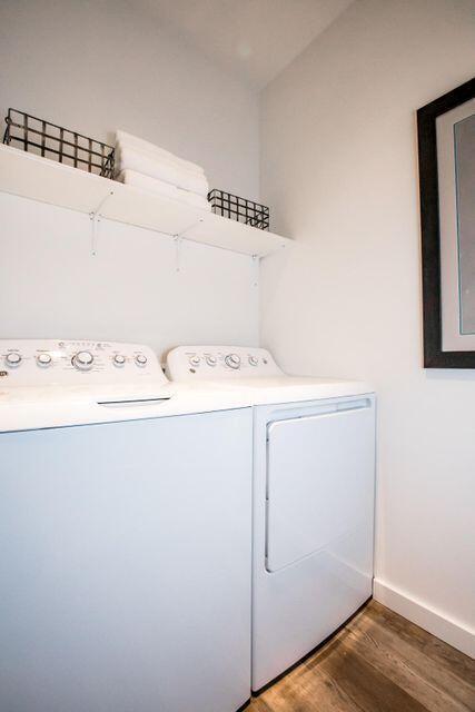 laundry area with washing machine and clothes dryer, wood finished floors, and baseboards
