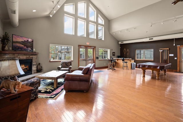 living room featuring track lighting, billiards, hardwood / wood-style floors, a fireplace, and high vaulted ceiling