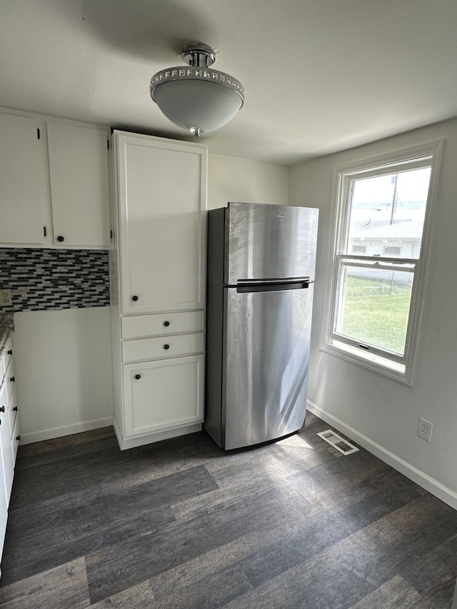 kitchen featuring freestanding refrigerator, white cabinetry, dark wood-type flooring, tasteful backsplash, and baseboards