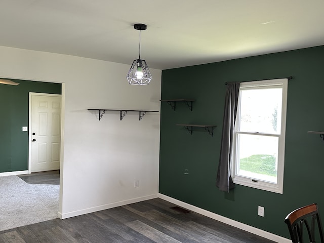 unfurnished dining area with dark wood-style flooring and baseboards