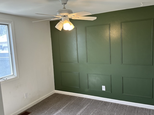 carpeted spare room featuring baseboards and ceiling fan