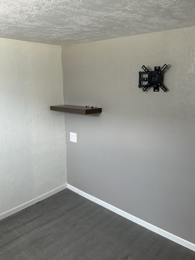 spare room with baseboards, a textured ceiling, and dark colored carpet