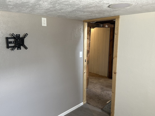 hallway with a textured ceiling and baseboards