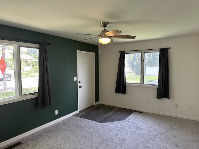 unfurnished room with dark colored carpet, ceiling fan, and baseboards