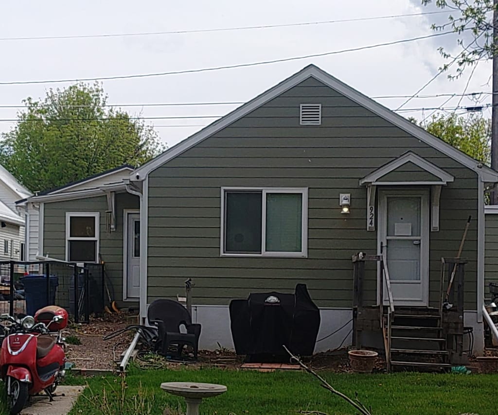 back of property with entry steps and a lawn