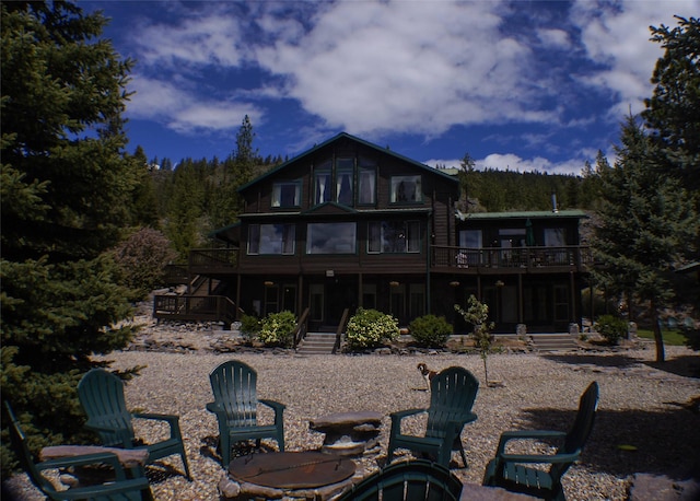 6961 Mt Highway 200, Plains, MT 59859 - rear view of house featuring stairs, a wooden deck, a fire pit, and a forest view