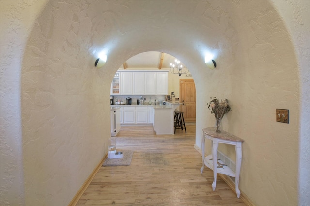 6961 Mt Highway 200, Plains, MT 59859 - corridor with a textured wall, arched walkways, light wood-type flooring, baseboards, and a chandelier