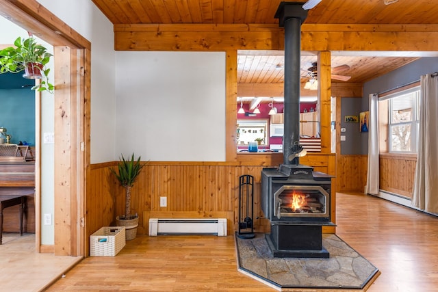 412 Mill St, Sheridan, MT 59749 - living room featuring a wood stove, a baseboard heating unit, wood walls, wooden ceiling, and wood finished floors
