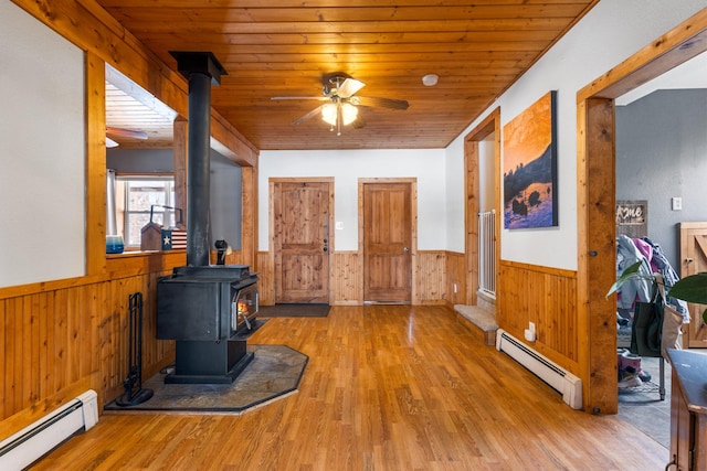 412 Mill St, Sheridan, MT 59749 - entryway with a baseboard radiator, wainscoting, a wood stove, a ceiling fan, and wood ceiling