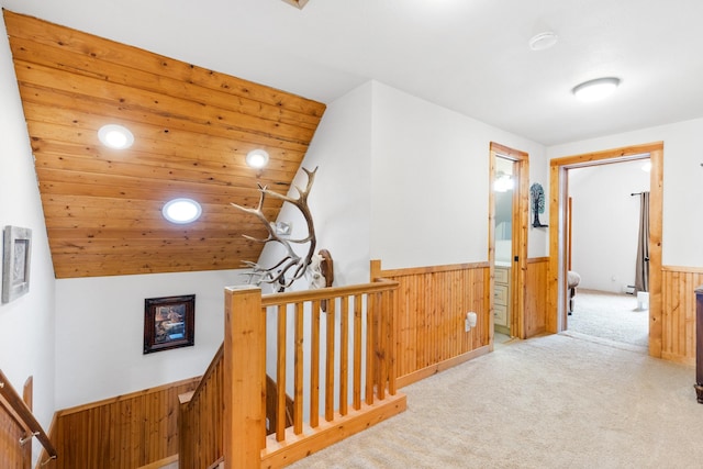 412 Mill St, Sheridan, MT 59749 - hallway featuring an upstairs landing, carpet floors, wainscoting, wooden walls, and vaulted ceiling