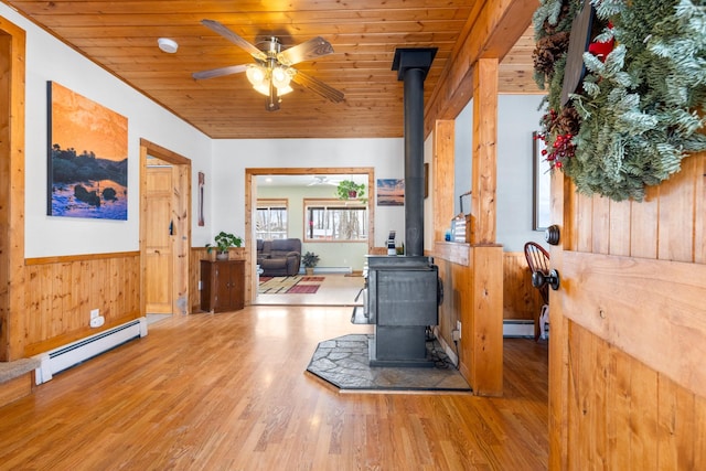 412 Mill St, Sheridan, MT 59749 - interior space featuring a wood stove, a baseboard heating unit, a wainscoted wall, wooden ceiling, and baseboard heating
